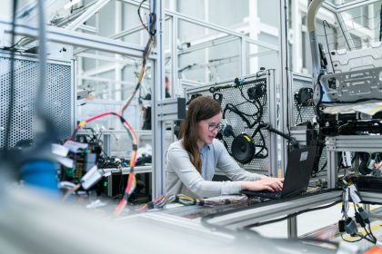 Engenheira trabalha em um laptop entre equipamentos tecnológicos avançados em um laboratório.