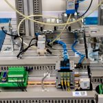 Close-up de equipamentos industriais com fiação eletrônica e sensores em uma instalação de manufatura.