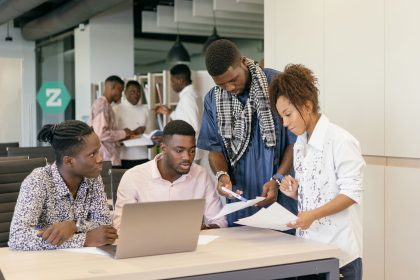Equipe diversa colaborando em um projeto diante de um computador em um escritório moderno.