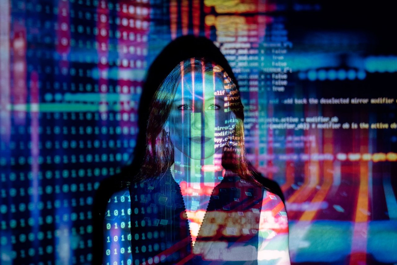 Mulher com projeções de código digital sobre o rosto, representando tecnologia e transformação digital.