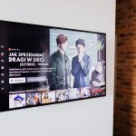 Televisão inteligente exibindo conteúdo de streaming em uma sala de estar moderna com parede de tijolos aparentes