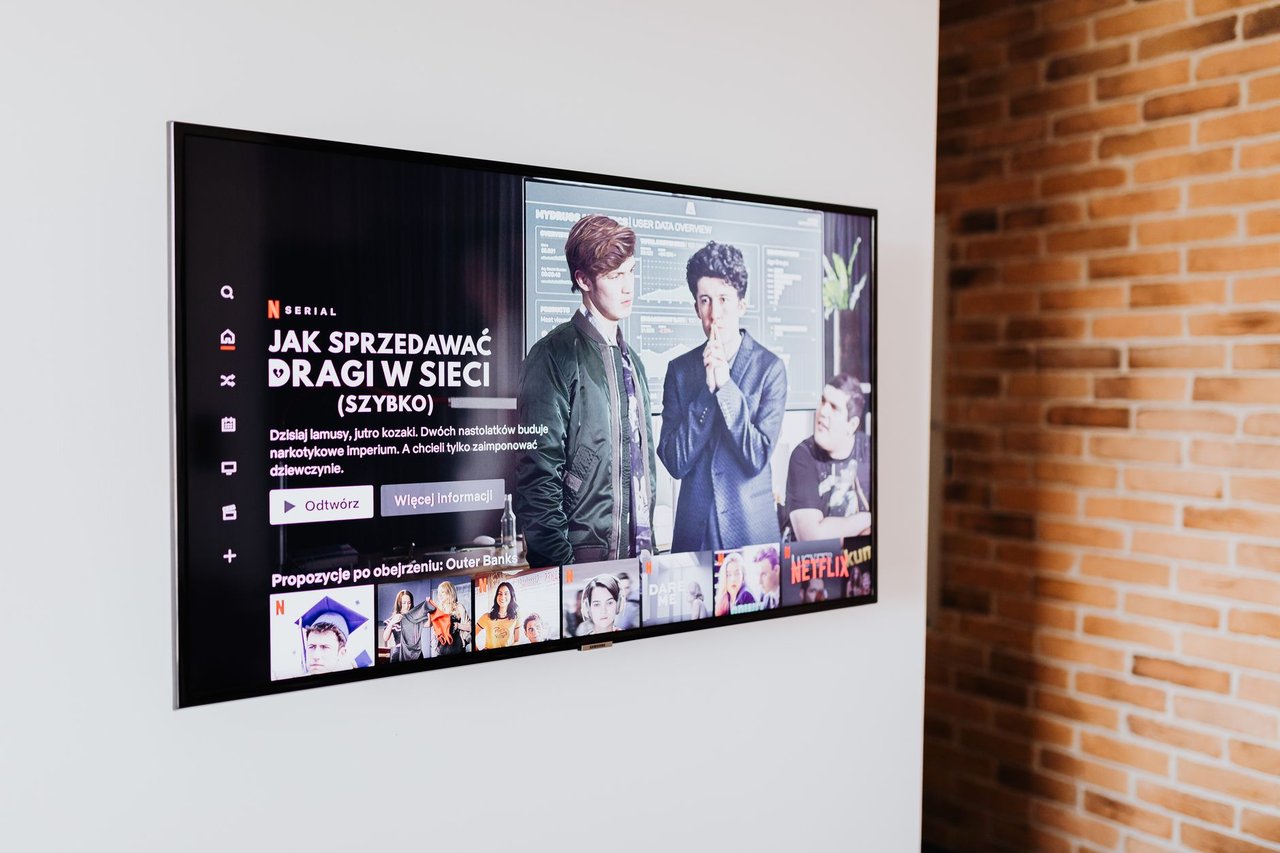 Televisão inteligente exibindo conteúdo de streaming em uma sala de estar moderna com parede de tijolos aparentes
