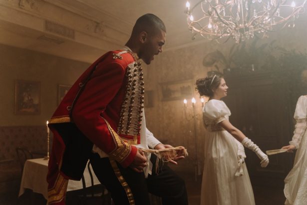 Pessoas em trajes de época dançam em um salão de baile histórico.
