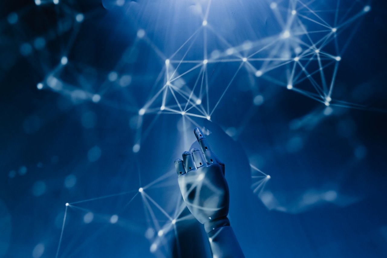 Mão robótica alcançando uma rede digital azul, em representação conceitual de inteligência artificial e tecnologia.
