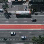 Vista aérea de uma via urbana movimentada, com carros, ônibus e ciclovias integrados ao sistema viário.