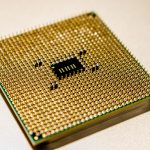 Close-up de um microprocessador dourado com detalhes de seus contatos e circuitos.