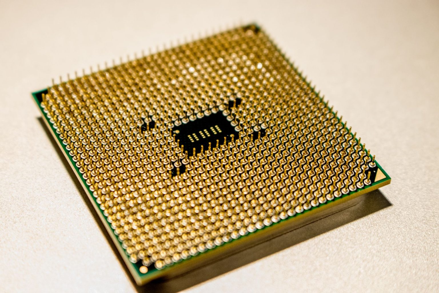 Close-up de um microprocessador dourado com detalhes de seus contatos e circuitos.